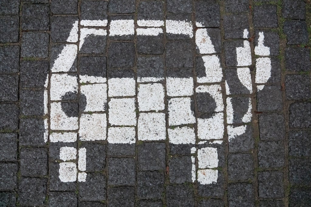 Ein Symbol markiert einen Parkplatz mit einer öffentlichen Ladesäule für Elektroautos.