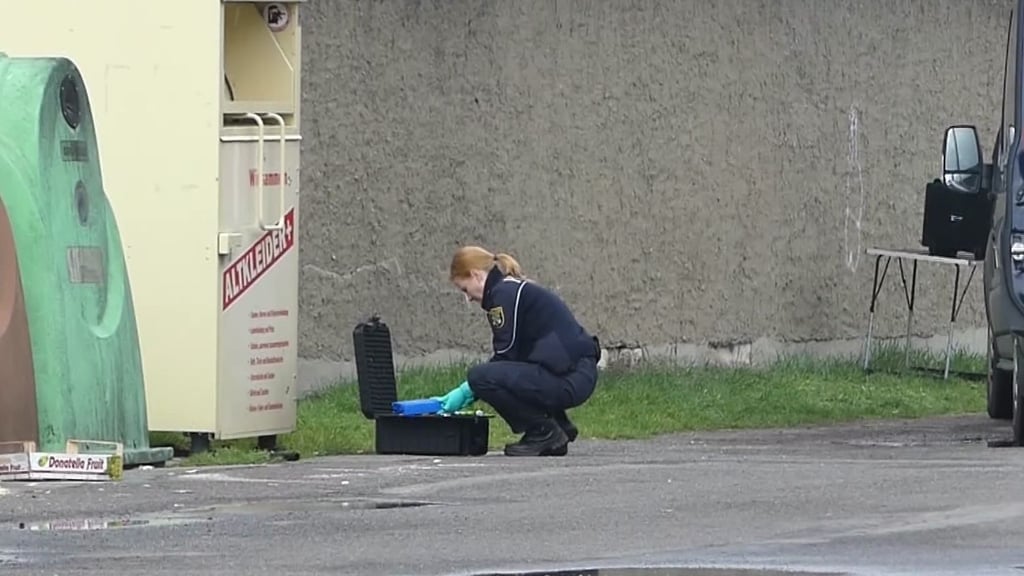 Eine Polizistin untersucht den Ort, an dem ein toter Säugling in einem Altkleidercontainer gefunden worden.