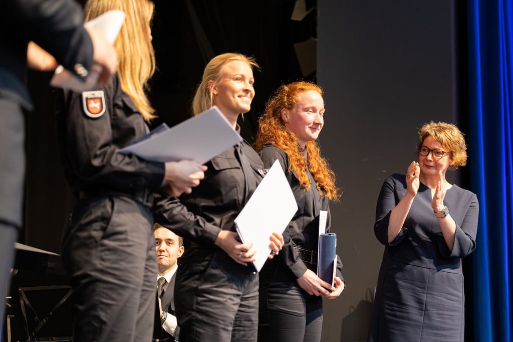 Daniela Behrens (SPD, r), Innenministerin Niedersachsen, steht neben Absolventen und Absolventinnen der Polizeiakademie.
