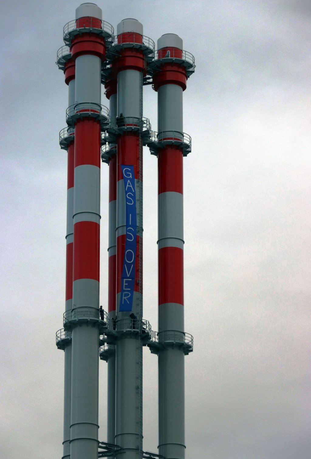 Aktivisten haben ein Transparent mit der Aufschrift „Gas is over“ auf den Schornsteinen des Heizkraftwerks befestigt.