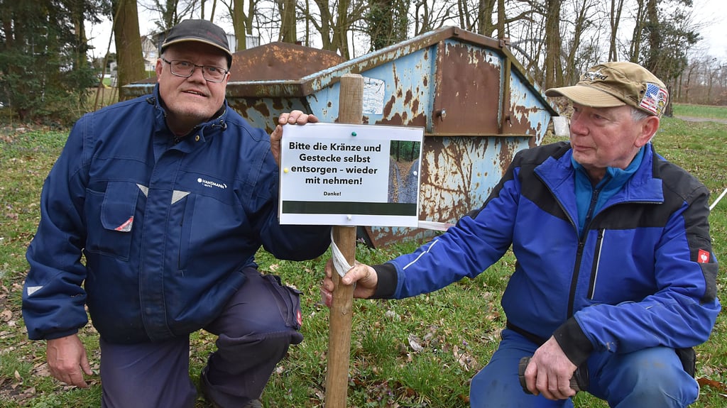 Klaus Dieter Sühring (l.) und Siegfried Gödicke stellen auf dem Calvörder Friedhof ein Schild auf. Darauf steht die Bitte, Kränze und Gestecke wieder mitzunehmen und selbst zu entsorgen.