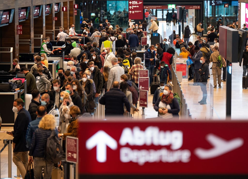 Zahlreiche Fluggäste warten im Terminal 1 des Flughafens BER in einer Schlange auf die Sicherheitskontrolle.