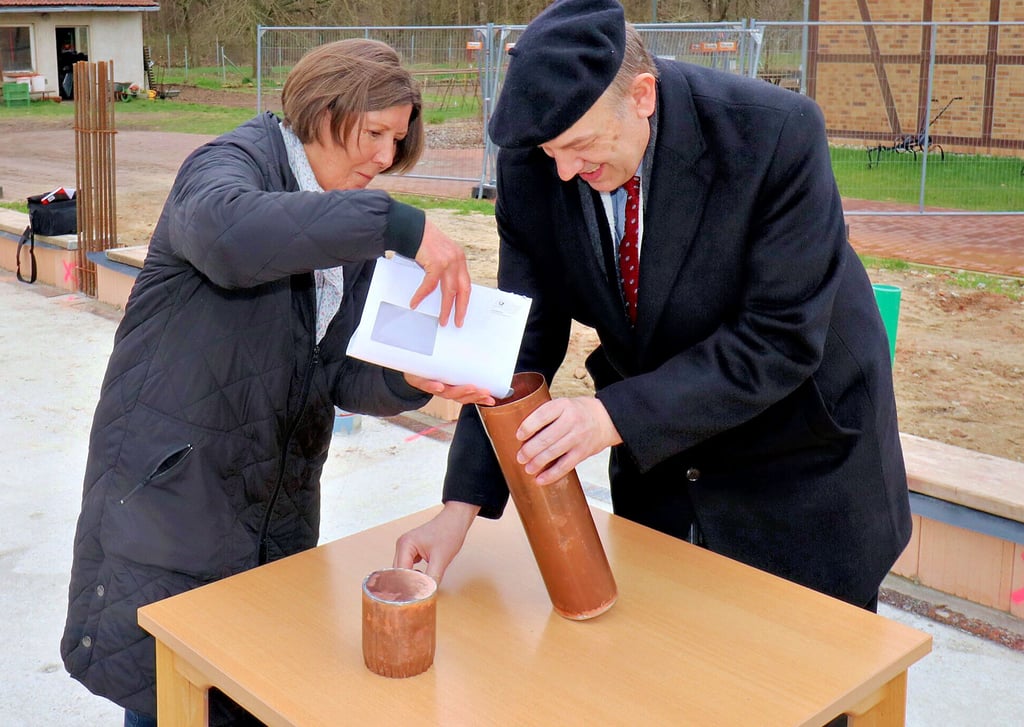 Kuratoriumsvorsitzende Martina Schwarzer und Diakon Andreas Gebhardt füllen die Hülse, die wenig später im Grundstein des Neubaus auf dem Seydaer Diest-Hof versenkt wird.