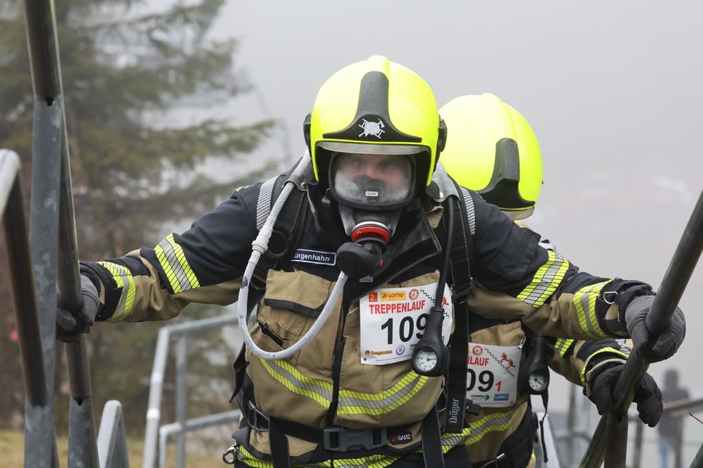 Feuerwehrleute laufen die Treppen der Lotto Thüringen Schanzenanlage hinauf.