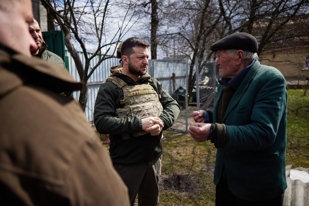 Wolodymyr Selenskyj (M) spricht mit Anwohnern in Butscha. Nach dem Abzug der russischen Truppen entdeckten die ukrainischen Behörden hier vor einem Jahr Hunderte Leichen.