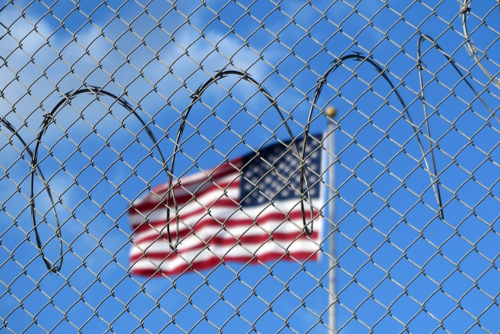 Eine US-Flagge hinter Zaun und Stacheldraht auf dem Marinestützpunkt Guantánamo Bay auf Kuba. Hier betreiben die USA seit mehr als 21 Jahren ein umstrittenes Gefangenenlager.