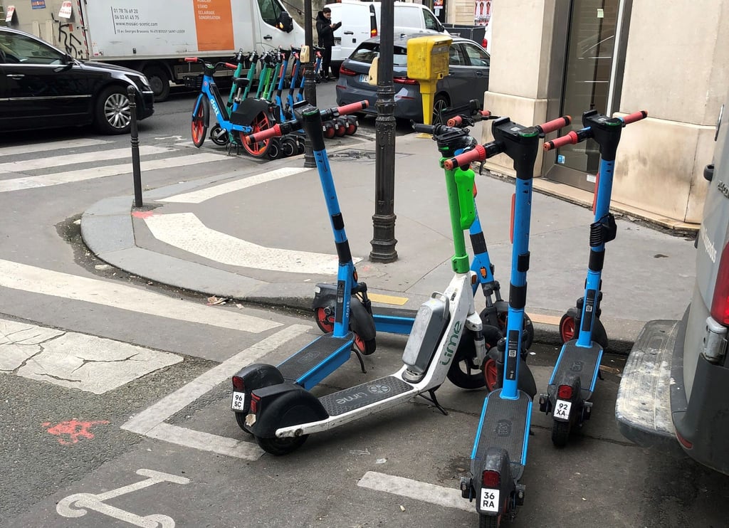 E-Scooter von drei verschiedenen Anbietern stehen auf dafür vorgesehenen Parkplätzen.