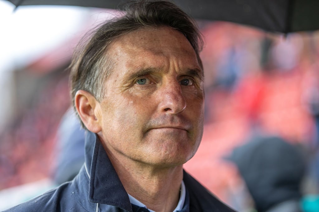 Trainer Bruno Labbadia vom VfB Stuttgart steht unter einem Regenschirm im Stadion.
