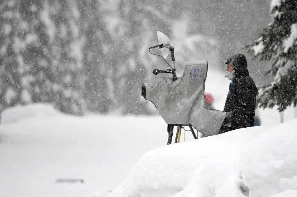 Ein TV-Kameramann steht im Schnee und filmt Wintersport.