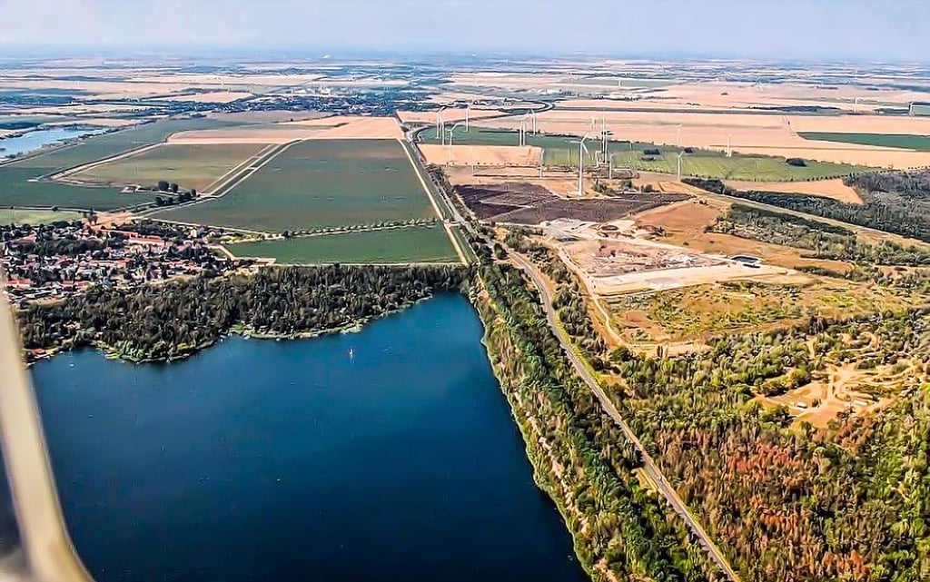 Auf dieser Luftaufnahme ist zu erkennen, dass die Grube direkt an die ehemalige B 100, die aktuelle B 100 und die Hochmülldeponie angrenzt.