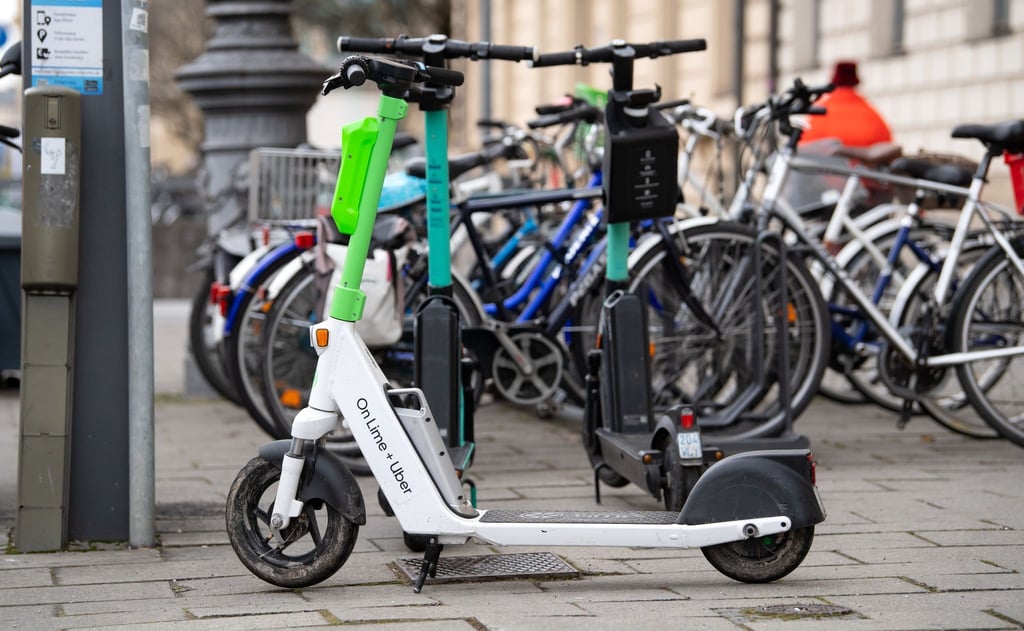 E-Scooter stehen in der Münchener Innenstadt auf einem Gehweg.