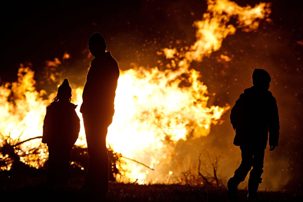 Ein Mann und zwei Kinder stehen vor einem Osterfeuer.