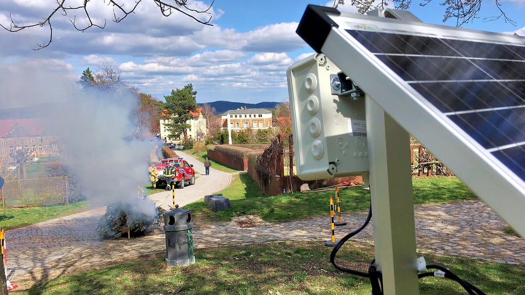 Testweise Schauvorführung mit viel Qualm: Im Garten der Blankenburger Schlossanlage entfachten Wehrmitglieder ein Feuer, um das Waldbrandsensorik-System – vorn rechts mit Sensorkasten und Solarpanel – einem Praxistest zu unterziehen.
