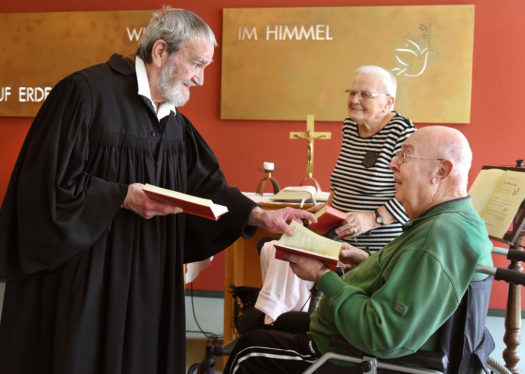 Im Andachtsraum des Martha-Hauses spricht der mit 80 Jahren älteste Bundesfreiwillige (Bufdi) Mitteldeutschlands Manfred Duncker (l) im Talar mit dem Heimbewohner-Ehepaar Ingrid (85)und Siegfried (83) Schlenkrich.