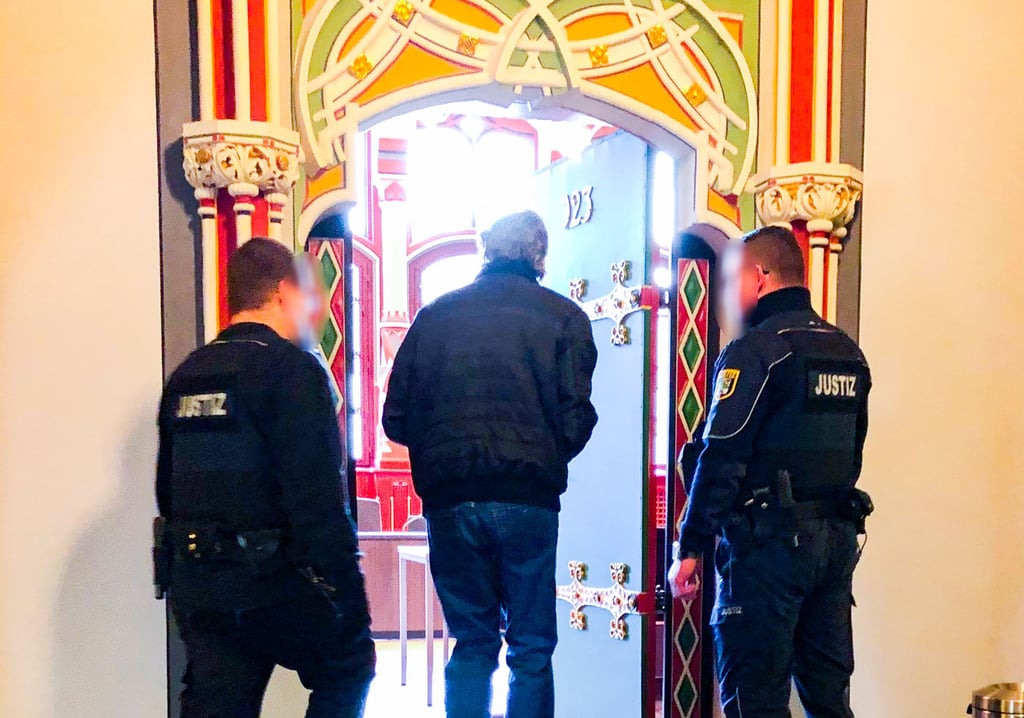 Der Angeklagte betritt gemeinsam mit Justizangestellten den Gerichtssaal im Landgericht.