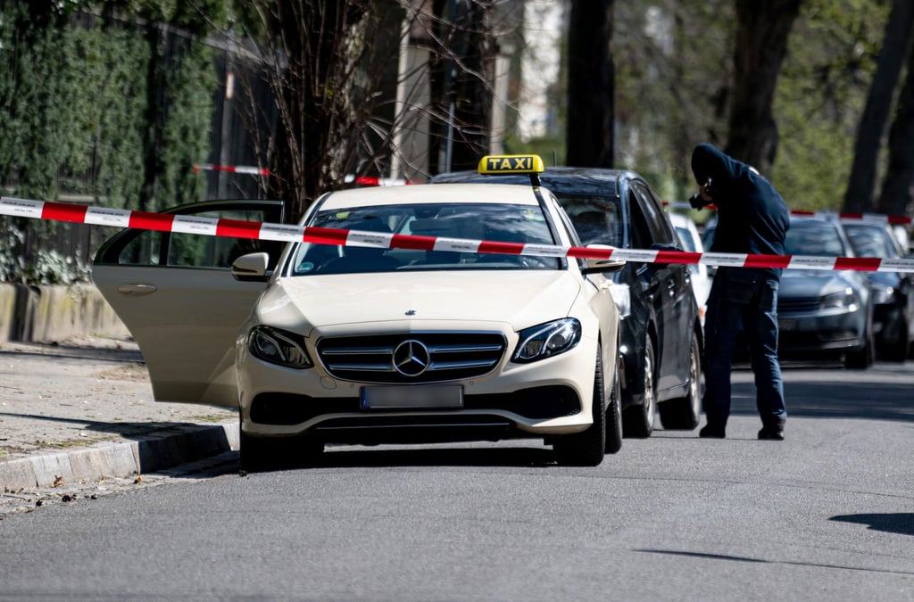 Mitarbeiter der Berliner Polizei steht vor einem Taxi in Berlin-Grunewald.