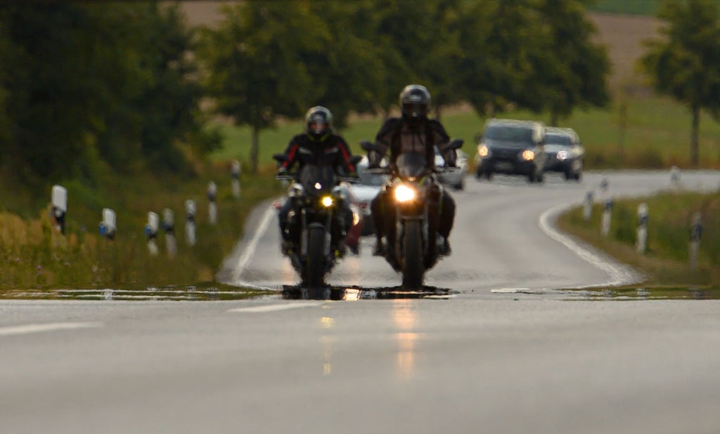 Zwei Biker fahren über eine Landstraße.