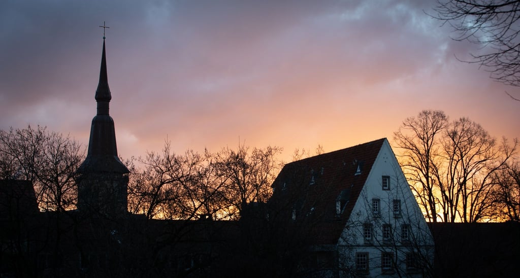 Die Sonne geht hinter der evangelisch-lutherischen Kirche St. Katharinen (l) auf.