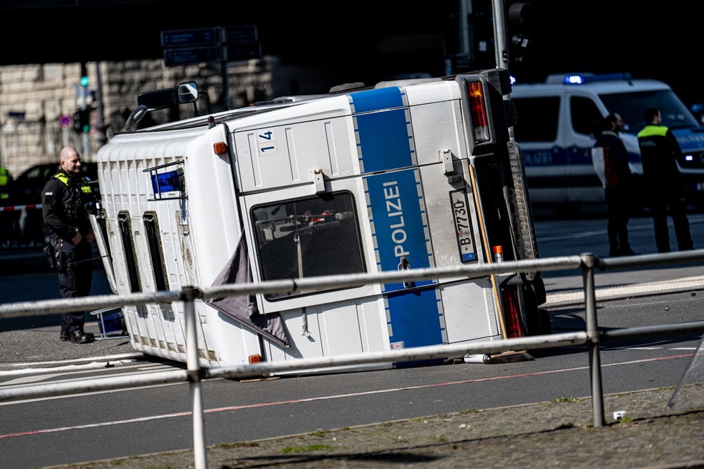 Ein umgekipptes Polizeifahrzeug liegt nach einem Unfall vor dem Bahnhof Zoo auf einer Kreuzung.
