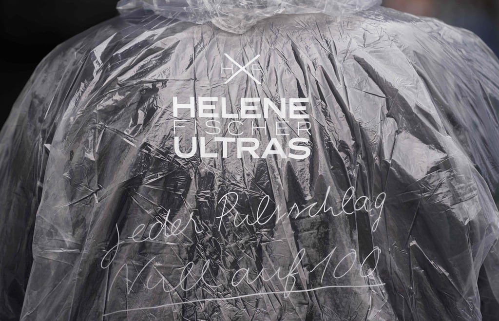 Ein Helene-Fischer-Fan steht mit einem Regenponcho und der Aufschrift „Helene Fischer Ultras - Jeder Pulsschlag null auf hundert“ vor der Barclays Arena in Hamburg.