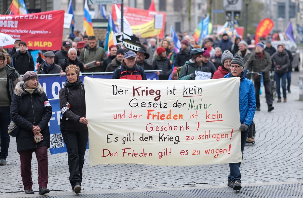 Teilnehmer einer Demonstration gehen mit Fahnen und Transparenten in Leipzig auf die Straße.