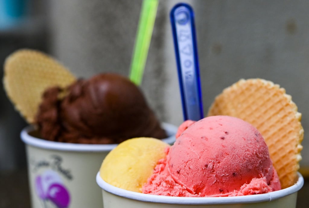 Eisbecher mit Kugeln verschiedener Sorten Eis stehen auf einem Tisch in einer Eisdiele.