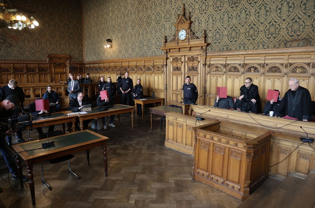 Vier Angeklagte warten in einem Saal des Landgerichtes in Bremen mit ihren Verteidigern auf ihren Prozessbeginn.