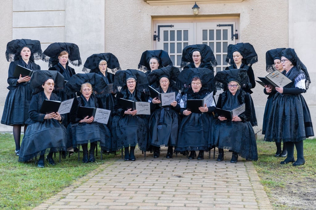 Frauen der Chorgemeinschaft Concordia singen in schwarzen Trachten am Ostersonntag vor der evangelischen Kirche im Spreewaldort Burg.