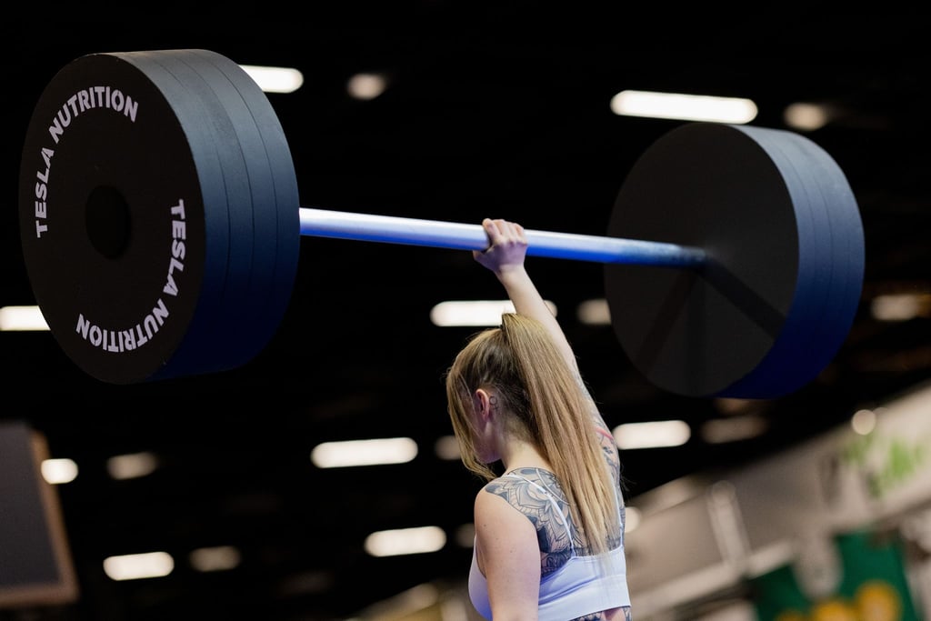 Eine Besucherin hebt an einem Messestand auf der Fitnessmesse Fibo eine Hantel aus Styropor hoch. Die Fibo ist die nach eigenen Angaben weltgrößte Messe für Fitness, Wellness und Gesundheit.