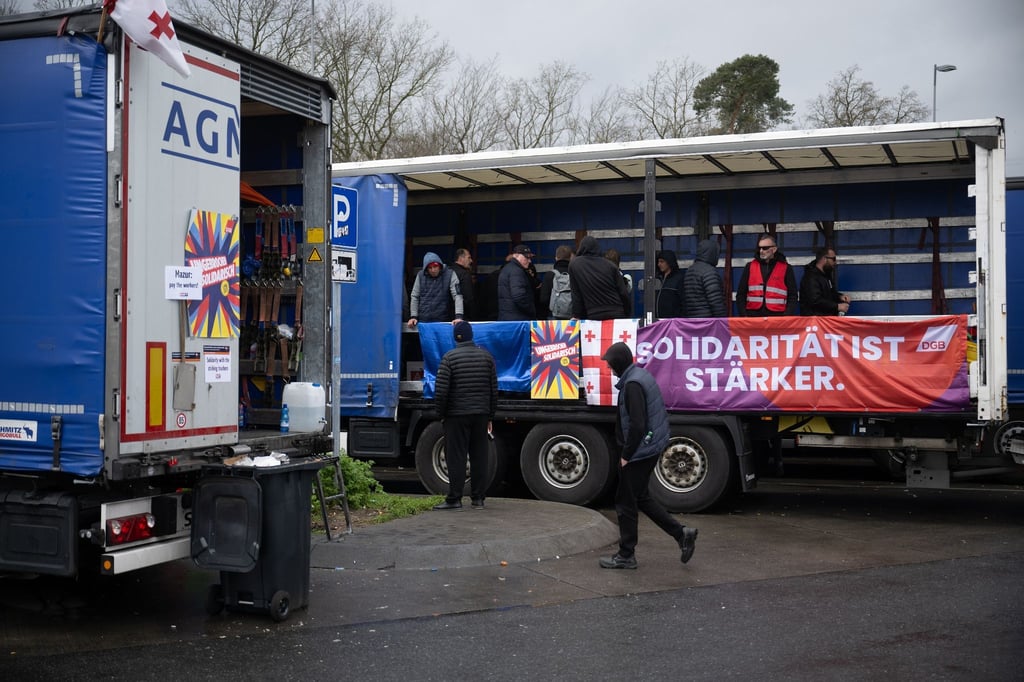„Solidarität ist stärker“ steht auf einem Banner. Die Lastwagenfahrer streiken auf einer Raststätte. Sie fordern ausstehenden Lohn von ihrem Arbeitgeber.
