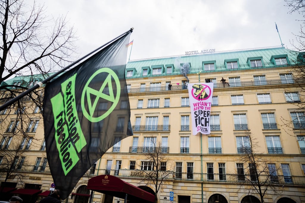 Aktivisten der Klimagruppe „Extinction Rebellion“ stehen auf einer Balustrade des Hotel Adlon mit einem Banner und Pyrotechnik.