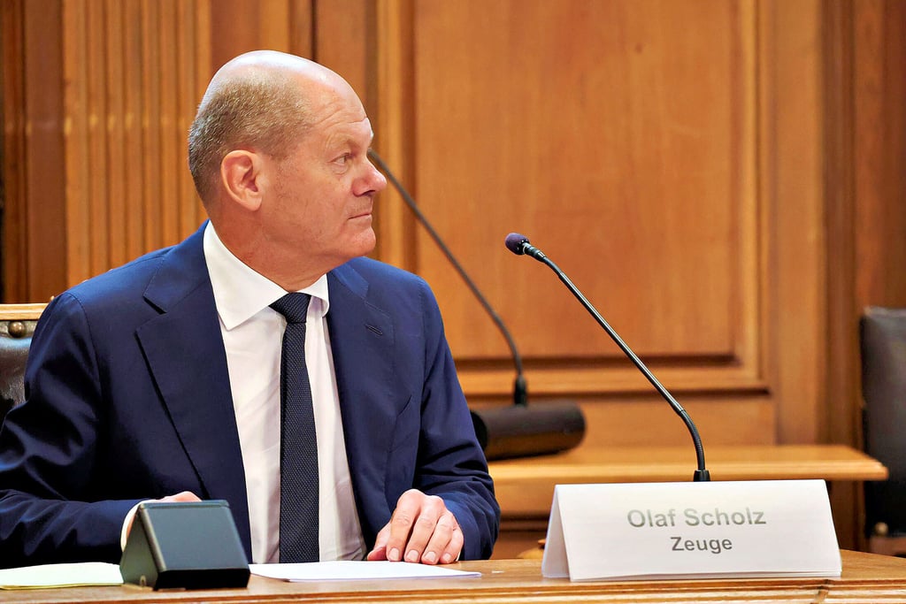 Bundeskanzler Olaf Scholz (SPD) sitzt am 19. August 2022 auf seinem Platz auf der Senatsbank mit einem Plastikschild mit dem Text „Olaf Scholz Zeuge“ vor dem Beginn einer Sitzung des U-Ausschusses „Cum-Ex“ im Hamburger Rathaus.