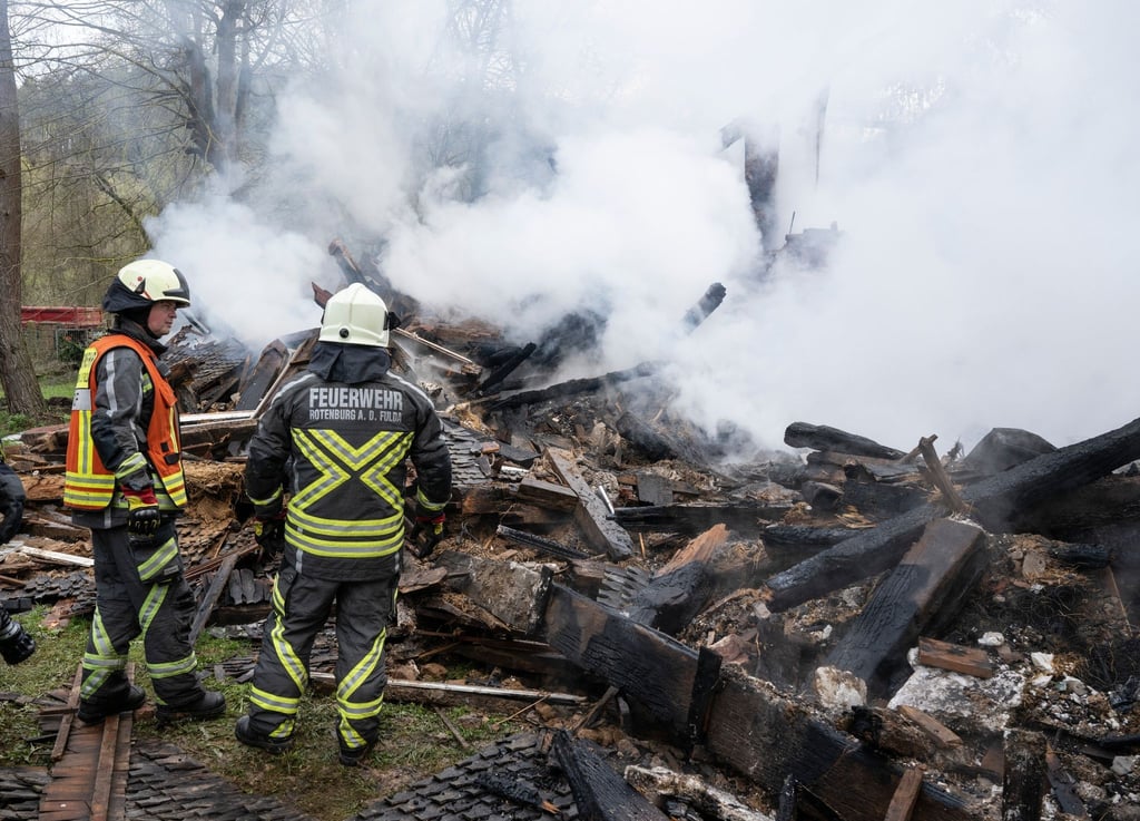 Feuerwehrleute stehen neben den noch rauchenden Trümmern des ehemaligen Hauses des „Kannibalen von Rotenburg“.