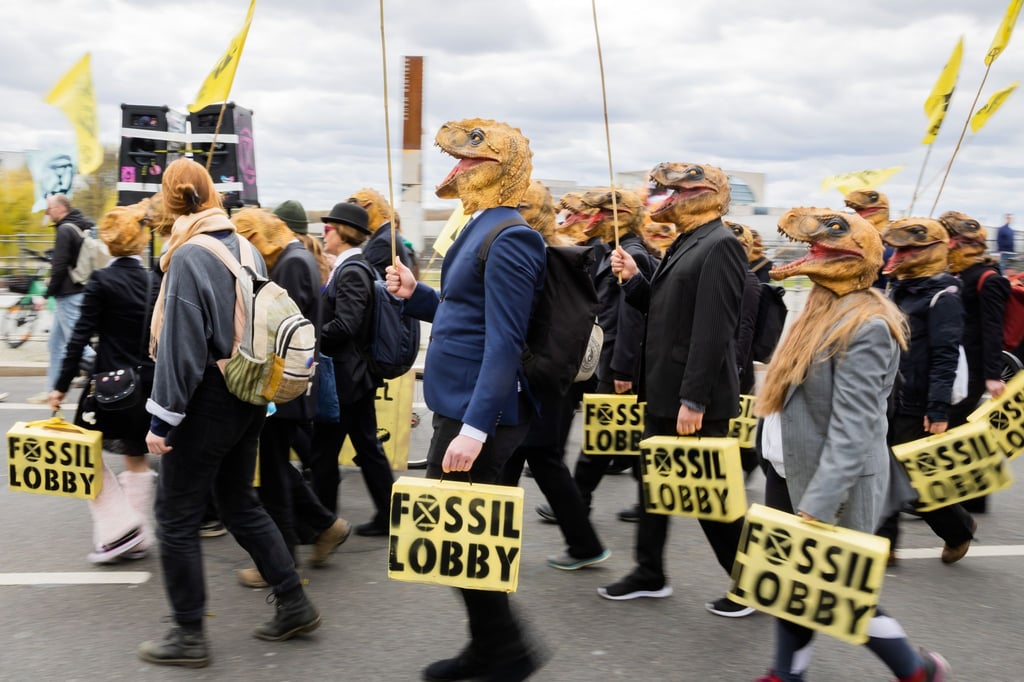 Teilnehmer einer Demonstration der Klimagruppe „Extinction Rebellion“ tragen Dinosaueriermasken.