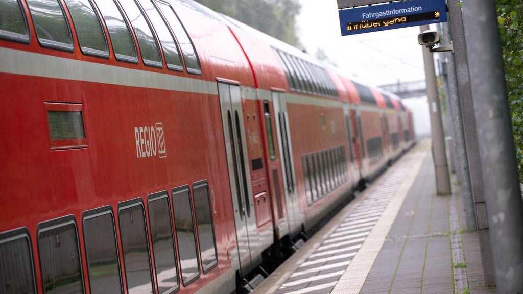 Ein doppelstöckiger Regionalzug der Deutschen Bahn fährt durch einen Bahnhof.