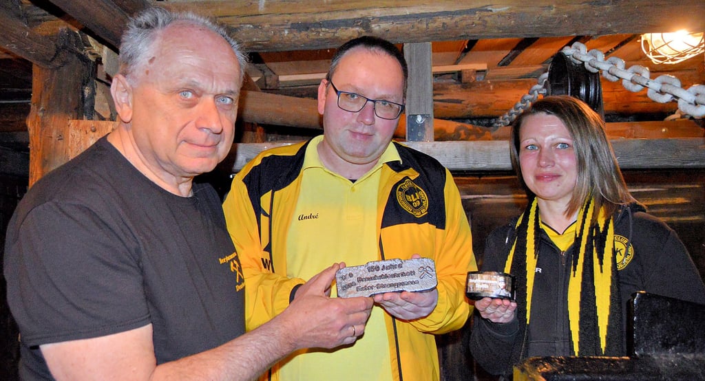 Von Frank Puschendorf (l.) bekamen die Fanclubvorsitzenden Kathleen Lita und André Wiedecke zwei Stück veredelte Kohle.