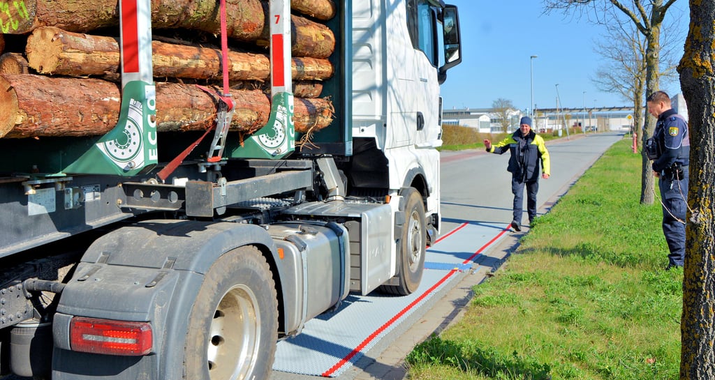 Kontrolle im Industriepark in Arneburg: Der Holztransporter muss nach und nach mit jeder Achse auf die Radlastwaage. Die Polizei hilft beim Jonglieren.