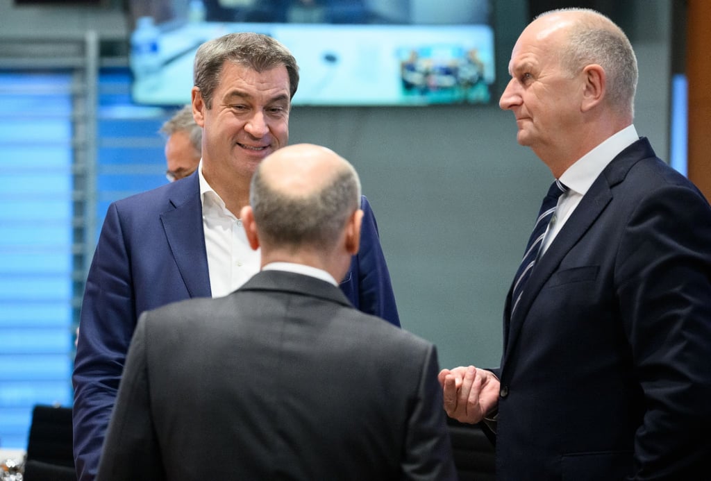 Markus Söder (l, CSU), Ministerpräsident von Bayern, Bundeskanzler Olaf Scholz (SPD) und Dietmar Woidke (r, SPD), Ministerpräsident von Brandenburg, unterhalten sich.