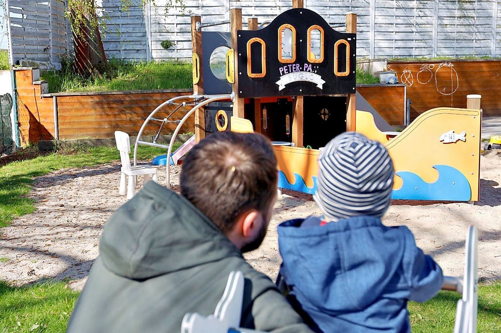 Sozialpädagoge Tobias Becker spielt mit einem kleinen Kind im Garten der Kinderschutzstelle.