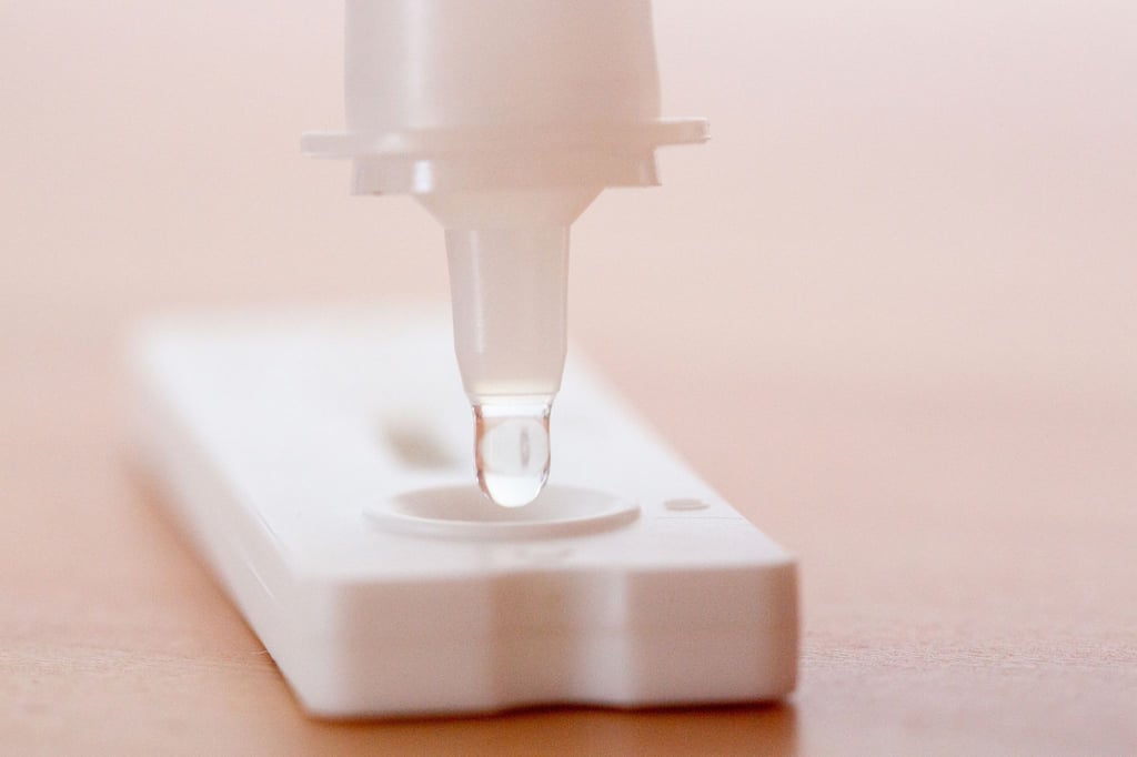 Flüssigkeit wird auf einen Antigen-Schnelltest gegeben.