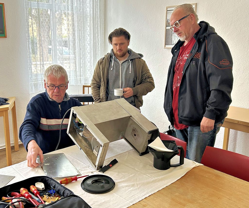Schrauber Walter Jung kümmert sich in Magdeburg-DIesdorf um die defekte Kaffeemaschine der Kita St. Martinstift, die Erzieher Felix Kirchner vorbeigebracht hat. Hilmar Knop wirft ebenfalls einen Blick darauf.