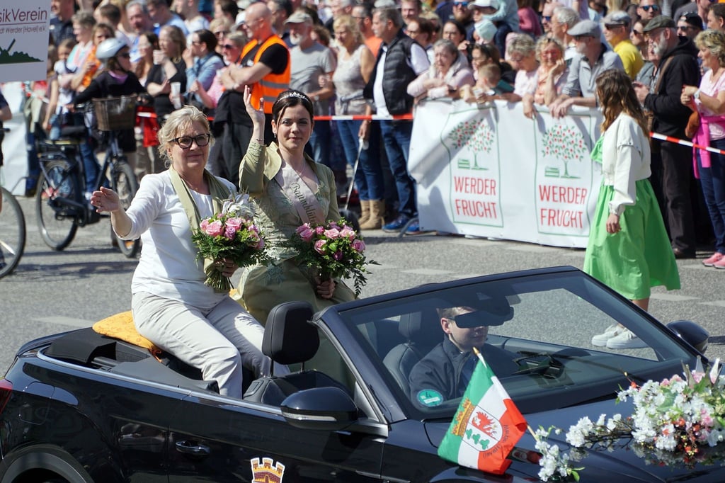 Werders Bürgermeisterin Manuela Saß (l) sitzt zusammen mit der neuen Baumblütenkönigin Doreen Vogler beim Festumzug des Baumblütenfestes Werder in einem Auto.