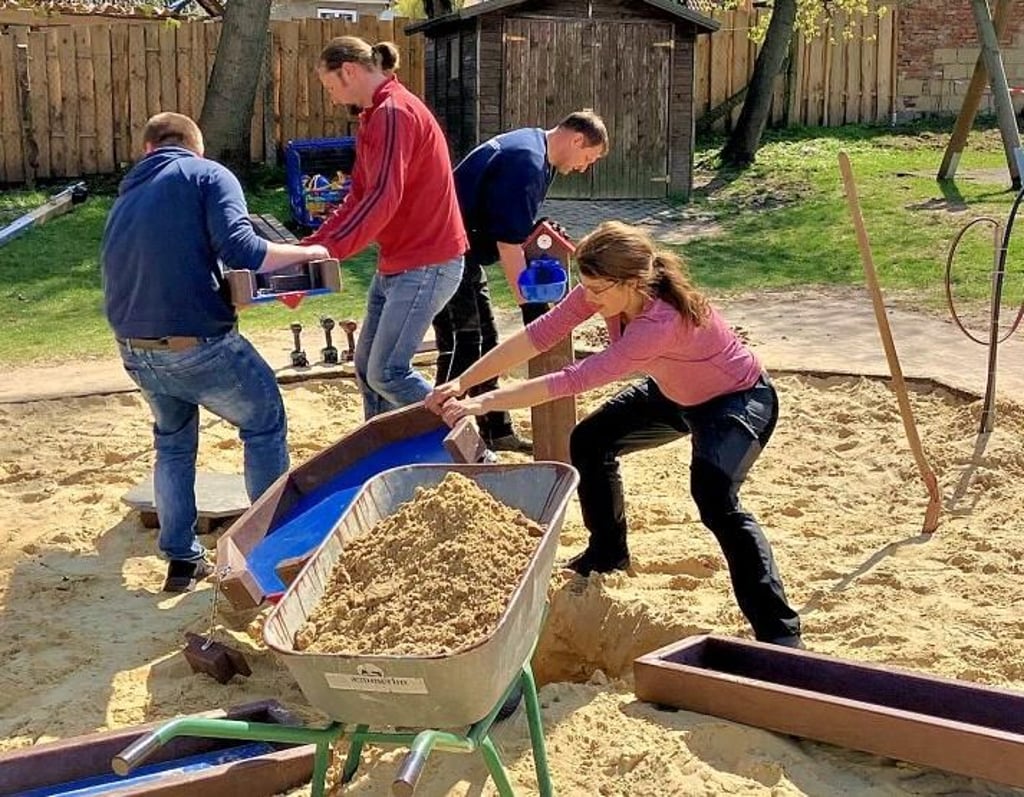 Eltern bauen die Wasserspielanlage auf dem neuen Spielplatz in Ballenstedt auf.