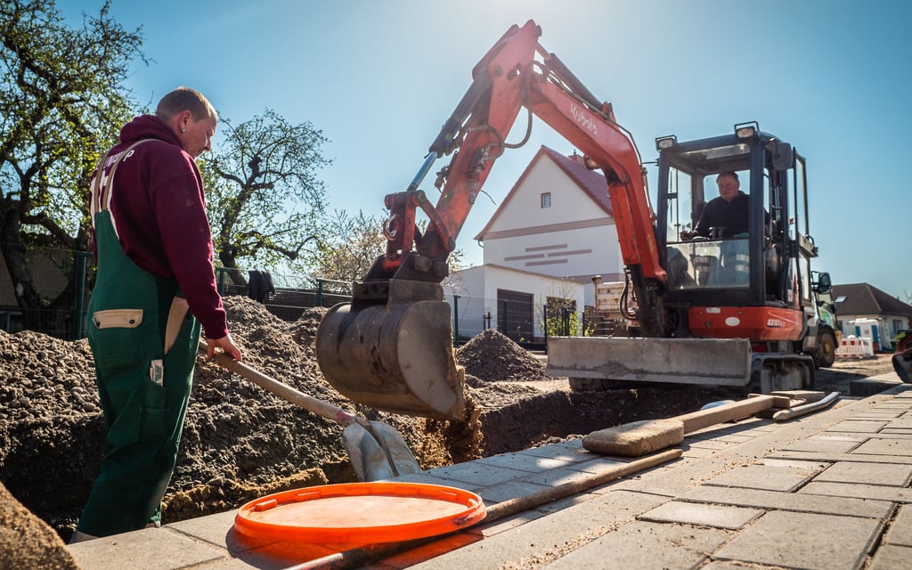Mirko Melcher (l.) und Roland Scholz im Bagger, Mitarbeiter der Firma Straßen- und Tiefbau Horst Grüning, sind dabei, in der Ernst-Thälmann-Straße in Gommern neue Regenwasserrohre zu verlegen. Bisher ist der Regen einfach auf der Straße abgelaufen.