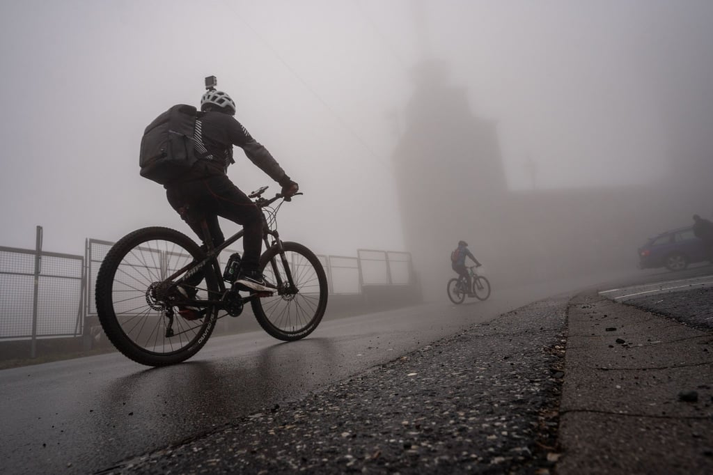Zwei Mountainbiker sind auf einer nassen Straße unterwegs.