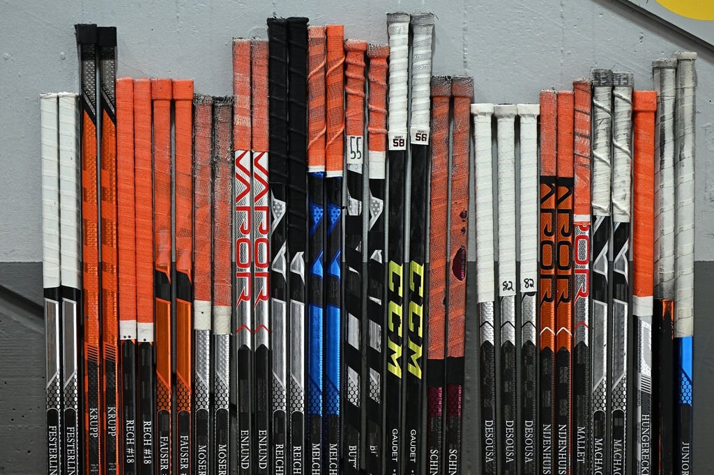 Eishockeyschläger stehen an der Bank bereit.