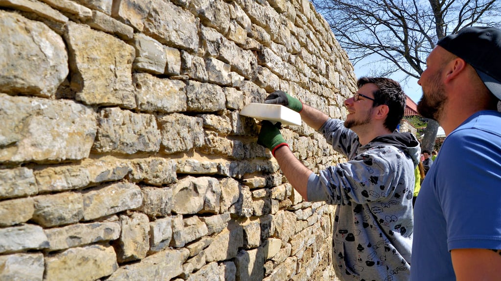 Tobias Friebertshäuser (r.) gibt Thomas Raudszus (l.) Hilfestellung bei der Arbeit an der Bruchsteinmauer.