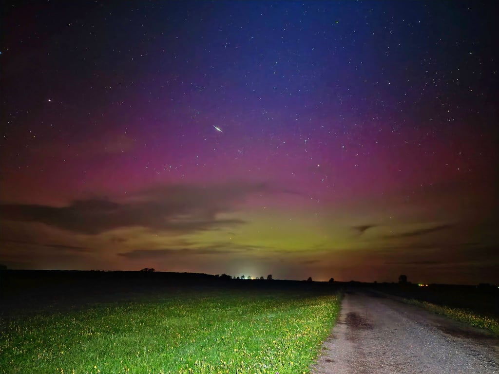 Ein Himmelskörper zieht durch die Polarlichter am nächtlichen Himmel.