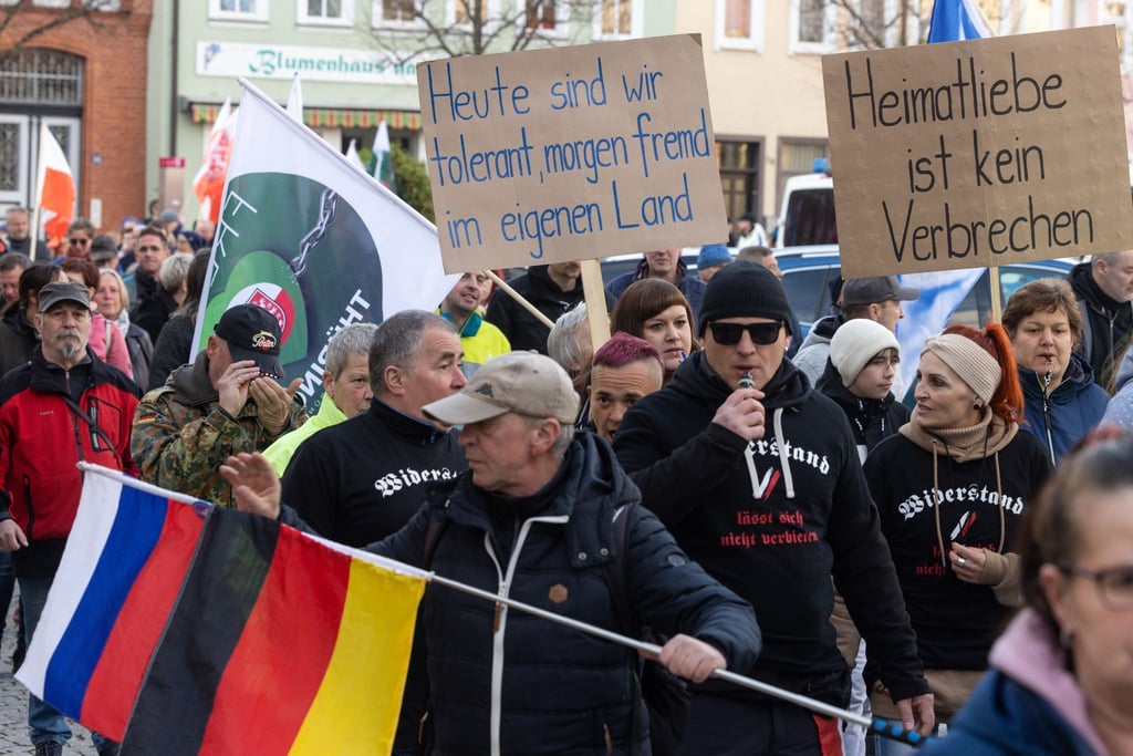 Menschen demonstrieren mit Transparenten und Fahnen gegen ein geplantes Flüchtlingsheim.