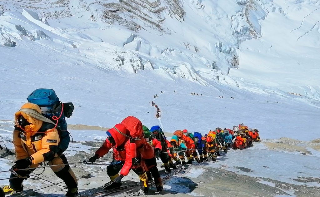 In einer langer Schlange klettern Bergsteiger auf einem Pfad am Mount Everest.